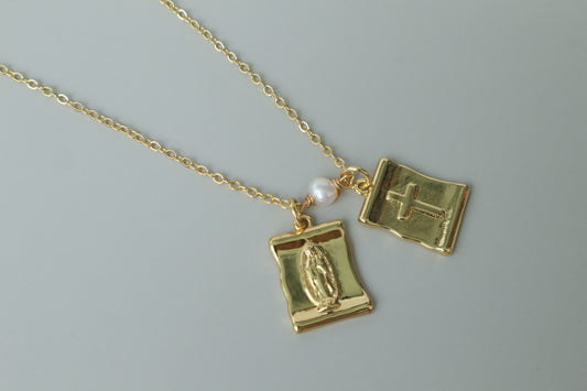 A gold-filled scapular pendant, a traditional symbol of faith, reimagined for modern wear. 