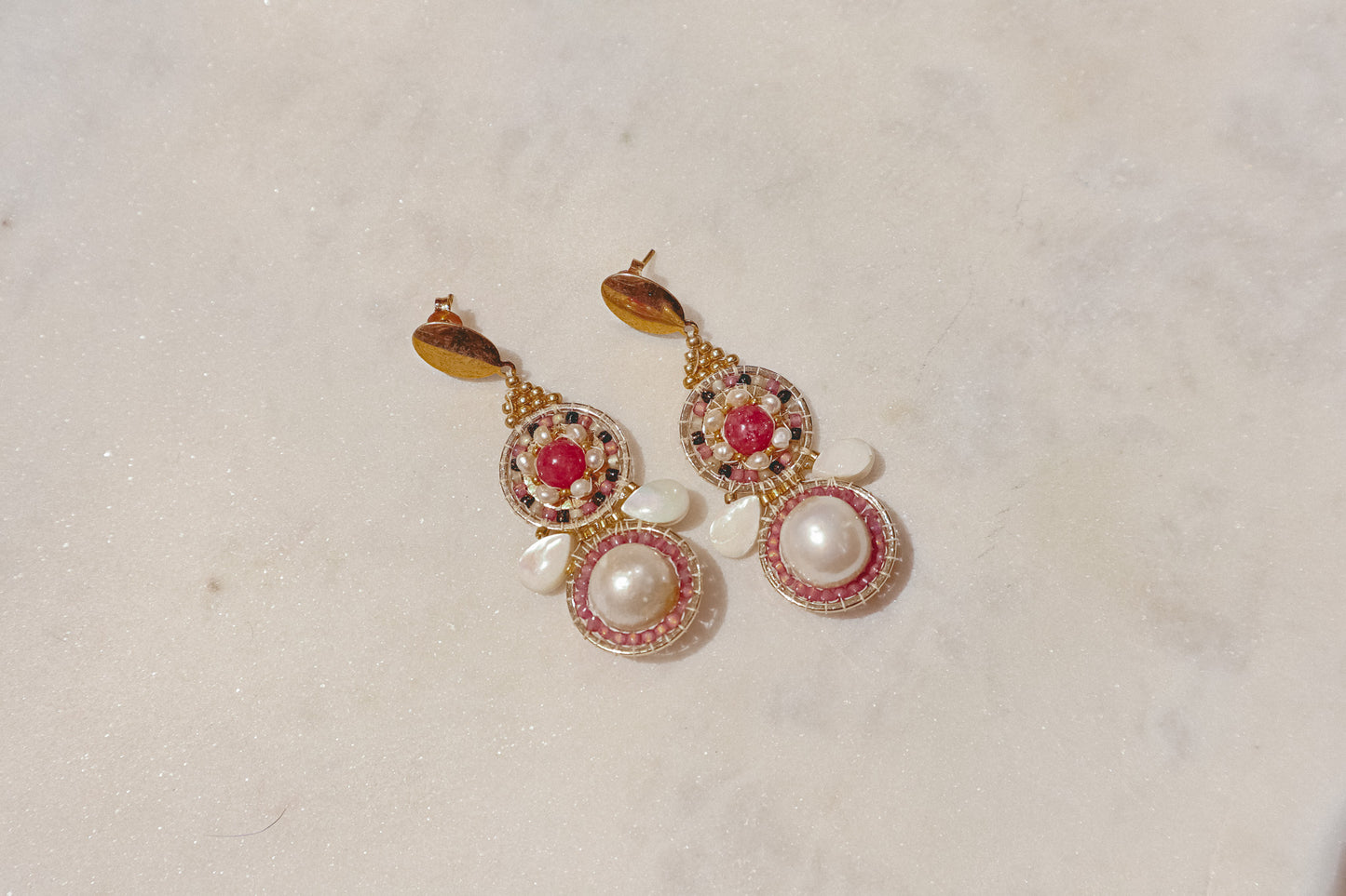 Celebrate a captivating interplay of texture, color, and light with these gold-filled earrings. Luminous freshwater pearls and delicate Keshi pearls offer a touch of timeless elegance. Shimmering strawberry quartz adds a hint of vibrant pink, while delicate mother-of-pearl teardrops boast an iridescent shimmer. Secured on gleaming gold-filled posts, these earrings are a captivating dance of pearl, quartz, and shell.