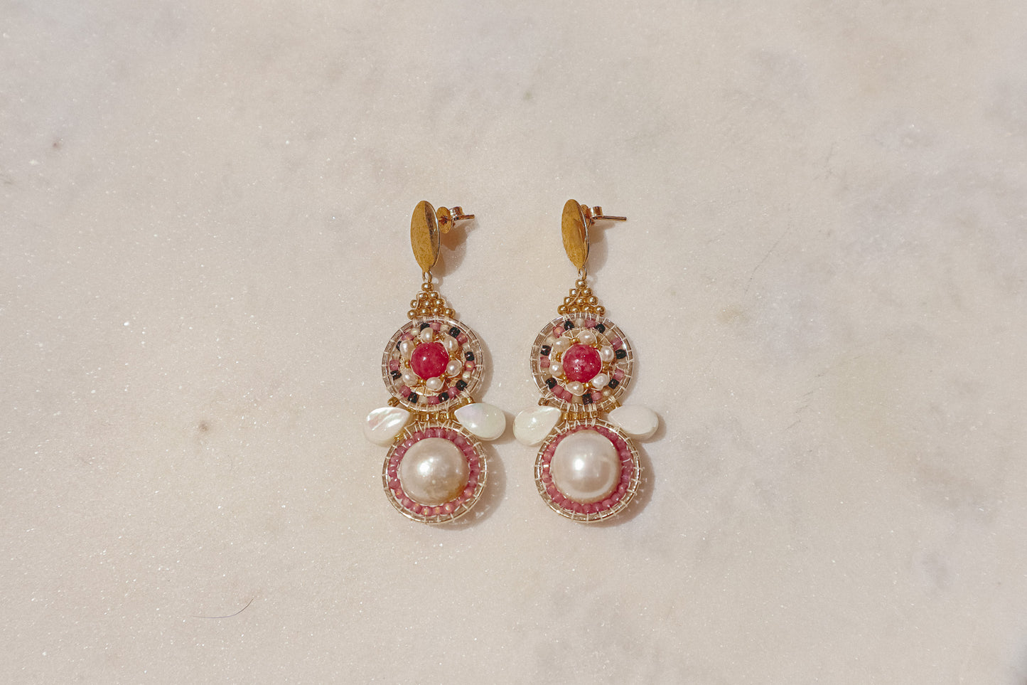 Celebrate a captivating interplay of texture, color, and light with these gold-filled earrings. Luminous freshwater pearls and delicate Keshi pearls offer a touch of timeless elegance. Shimmering strawberry quartz adds a hint of vibrant pink, while delicate mother-of-pearl teardrops boast an iridescent shimmer. Secured on gleaming gold-filled posts, these earrings are a captivating dance of pearl, quartz, and shell.