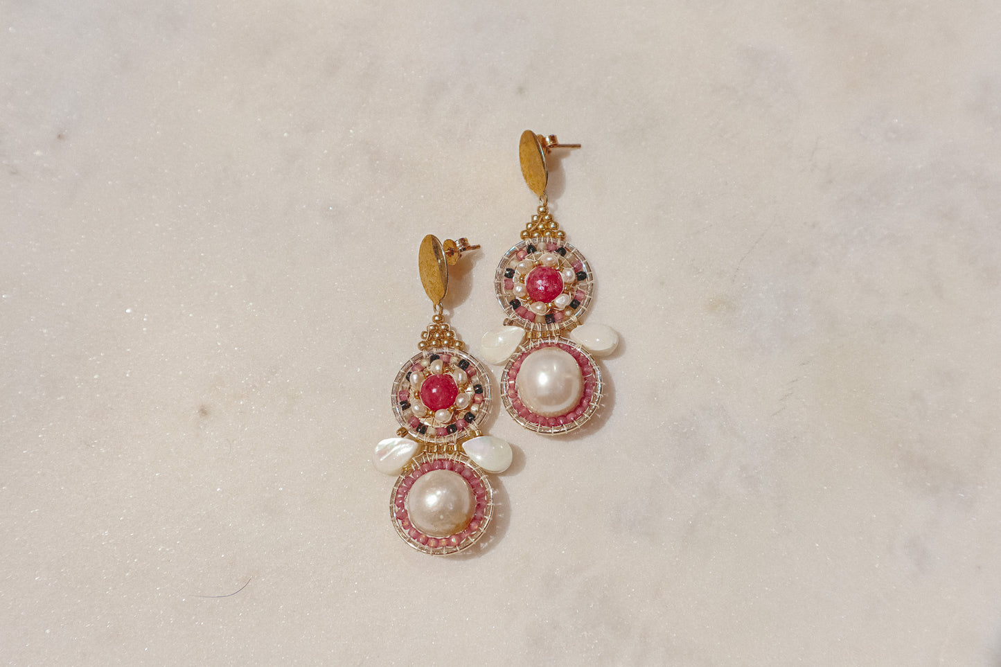 Celebrate a captivating interplay of texture, color, and light with these gold-filled earrings. Luminous freshwater pearls and delicate Keshi pearls offer a touch of timeless elegance. Shimmering strawberry quartz adds a hint of vibrant pink, while delicate mother-of-pearl teardrops boast an iridescent shimmer. Secured on gleaming gold-filled posts, these earrings are a captivating dance of pearl, quartz, and shell.