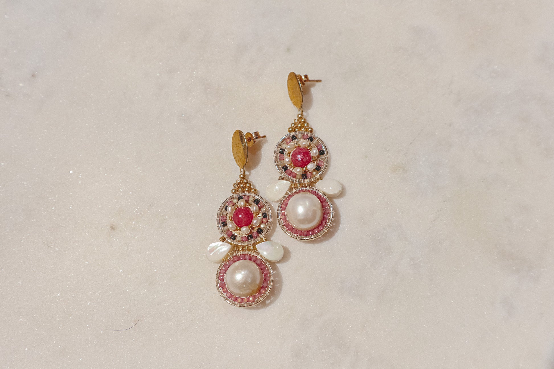 Celebrate a captivating interplay of texture, color, and light with these gold-filled earrings. Luminous freshwater pearls and delicate Keshi pearls offer a touch of timeless elegance. Shimmering strawberry quartz adds a hint of vibrant pink, while delicate mother-of-pearl teardrops boast an iridescent shimmer. Secured on gleaming gold-filled posts, these earrings are a captivating dance of pearl, quartz, and shell.