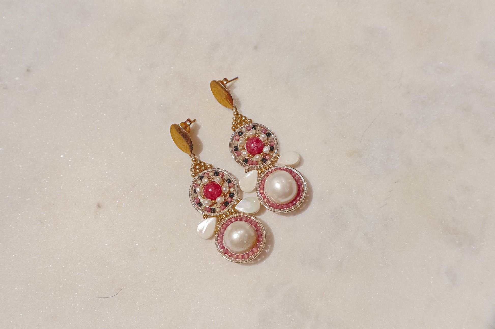 Celebrate a captivating interplay of texture, color, and light with these gold-filled earrings. Luminous freshwater pearls and delicate Keshi pearls offer a touch of timeless elegance. Shimmering strawberry quartz adds a hint of vibrant pink, while delicate mother-of-pearl teardrops boast an iridescent shimmer. Secured on gleaming gold-filled posts, these earrings are a captivating dance of pearl, quartz, and shell.