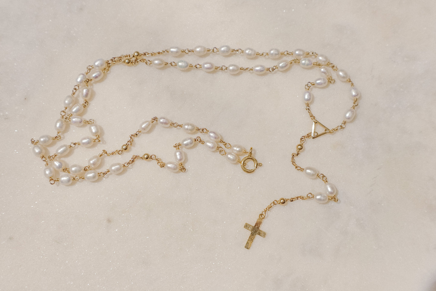 Luminous pearls, timeless symbols of purity and faith, adorn a delicate gold-filled wire chain.
