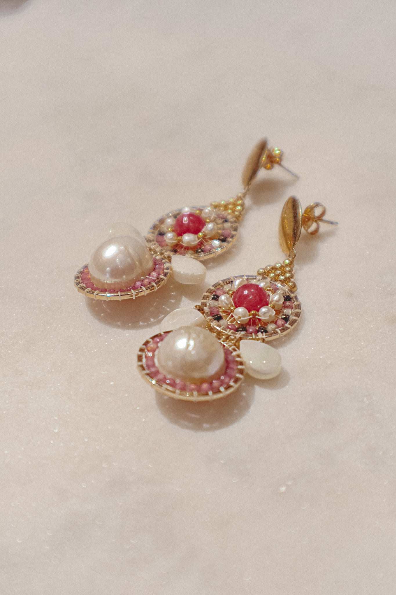 Celebrate a captivating interplay of texture, color, and light with these gold-filled earrings. Luminous freshwater pearls and delicate Keshi pearls offer a touch of timeless elegance. Shimmering strawberry quartz adds a hint of vibrant pink, while delicate mother-of-pearl teardrops boast an iridescent shimmer. Secured on gleaming gold-filled posts, these earrings are a captivating dance of pearl, quartz, and shell.