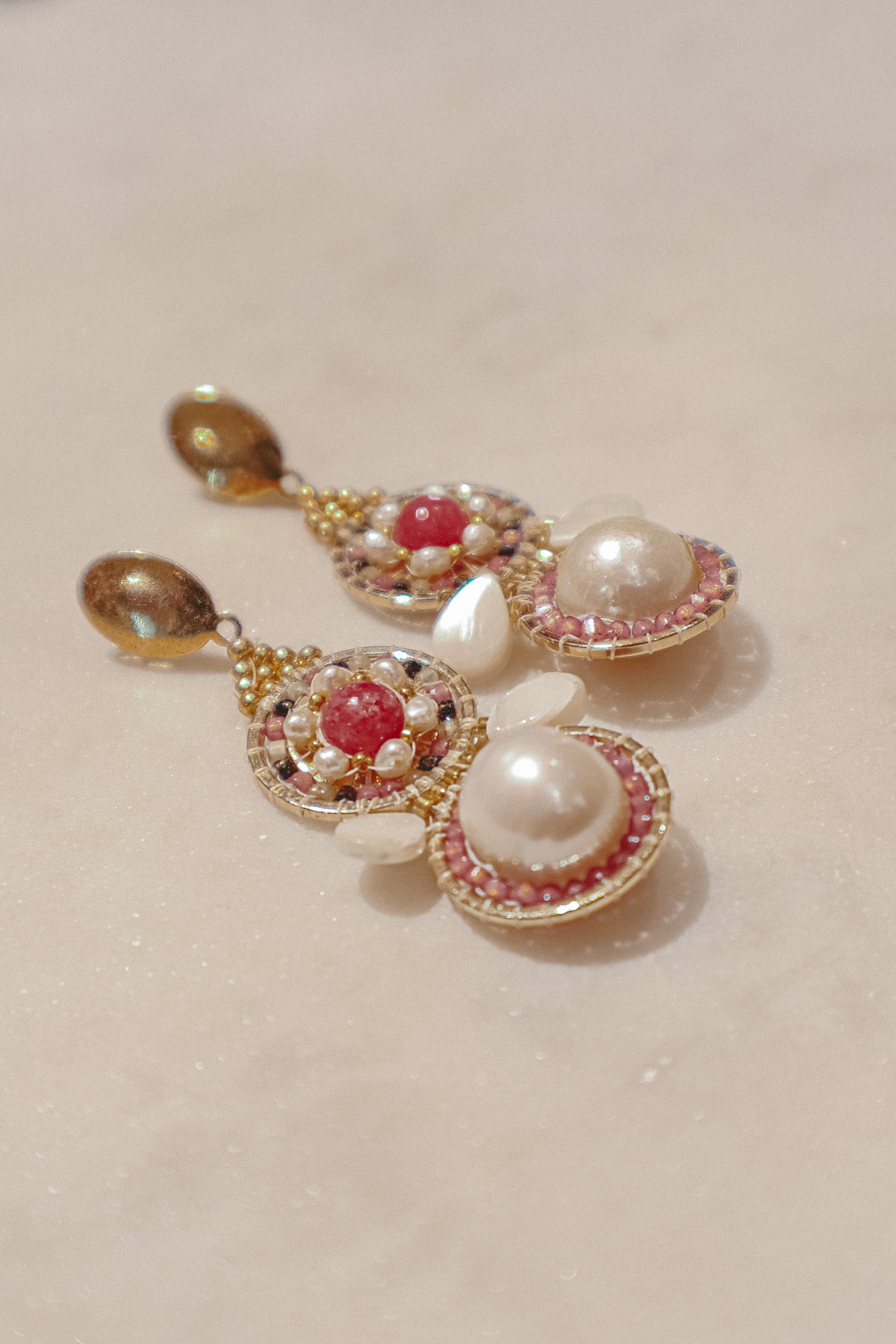 Celebrate a captivating interplay of texture, color, and light with these gold-filled earrings. Luminous freshwater pearls and delicate Keshi pearls offer a touch of timeless elegance. Shimmering strawberry quartz adds a hint of vibrant pink, while delicate mother-of-pearl teardrops boast an iridescent shimmer. Secured on gleaming gold-filled posts, these earrings are a captivating dance of pearl, quartz, and shell.