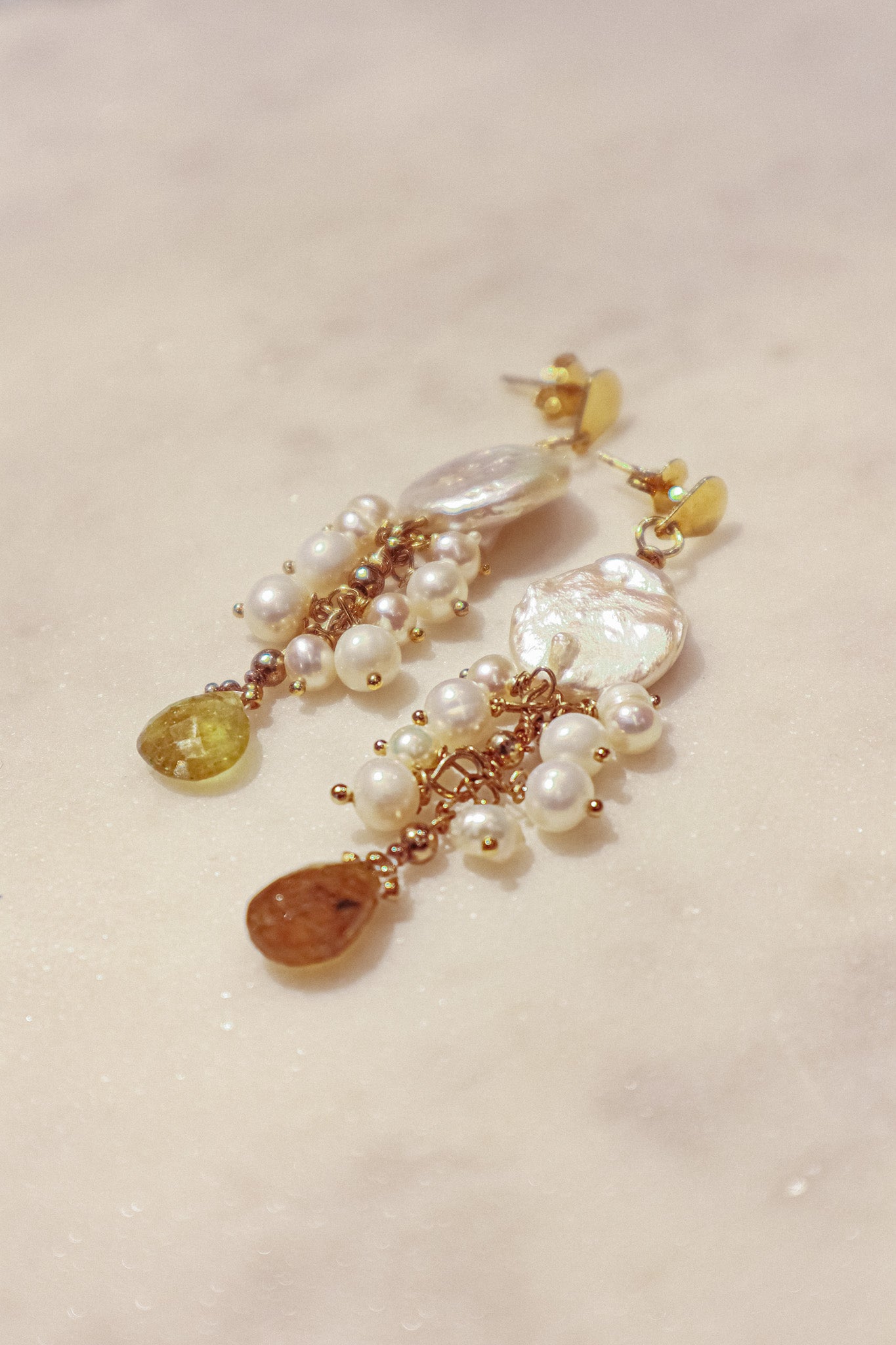 Embrace the organic elegance of these one-of-a-kind earrings. Baroque and freshwater pearls, boasting their unique shapes and textures, are meticulously woven together on sleek gold-filled findings. Shimmering Vessonite teardrops add a touch of vibrant green, creating a captivating contrast that reflects the beauty of nature's symphony.