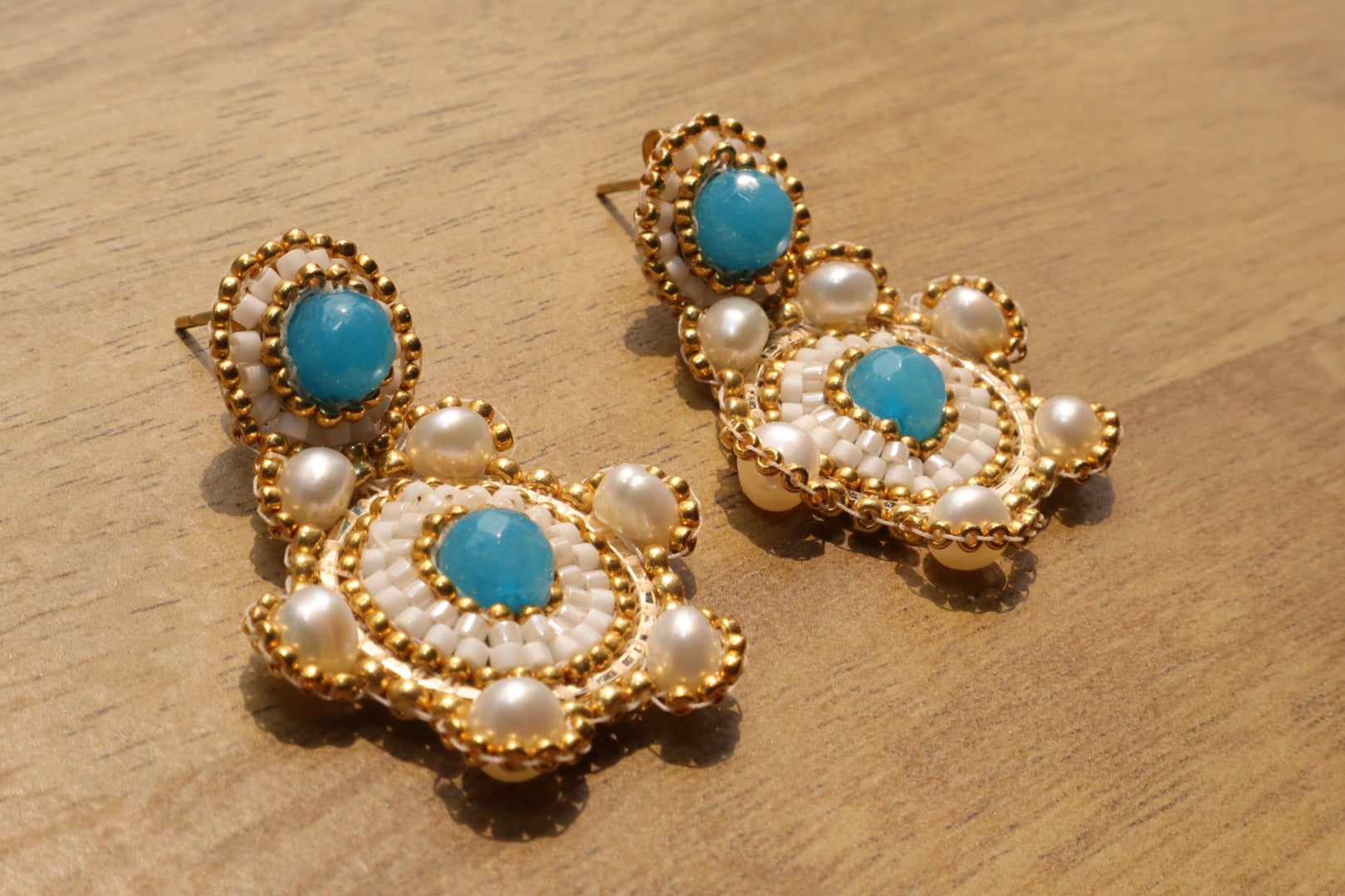 Blue Agate with Fresh Water Pearls on Gold-Filled hardware.  Soothing blue agate stones, reminiscent of cool ocean water, are nestled alongside luminous freshwater pearls. Each element is meticulously crafted in gleaming gold-filled hardware, creating a touch of ocean-inspired elegance for any occasion.