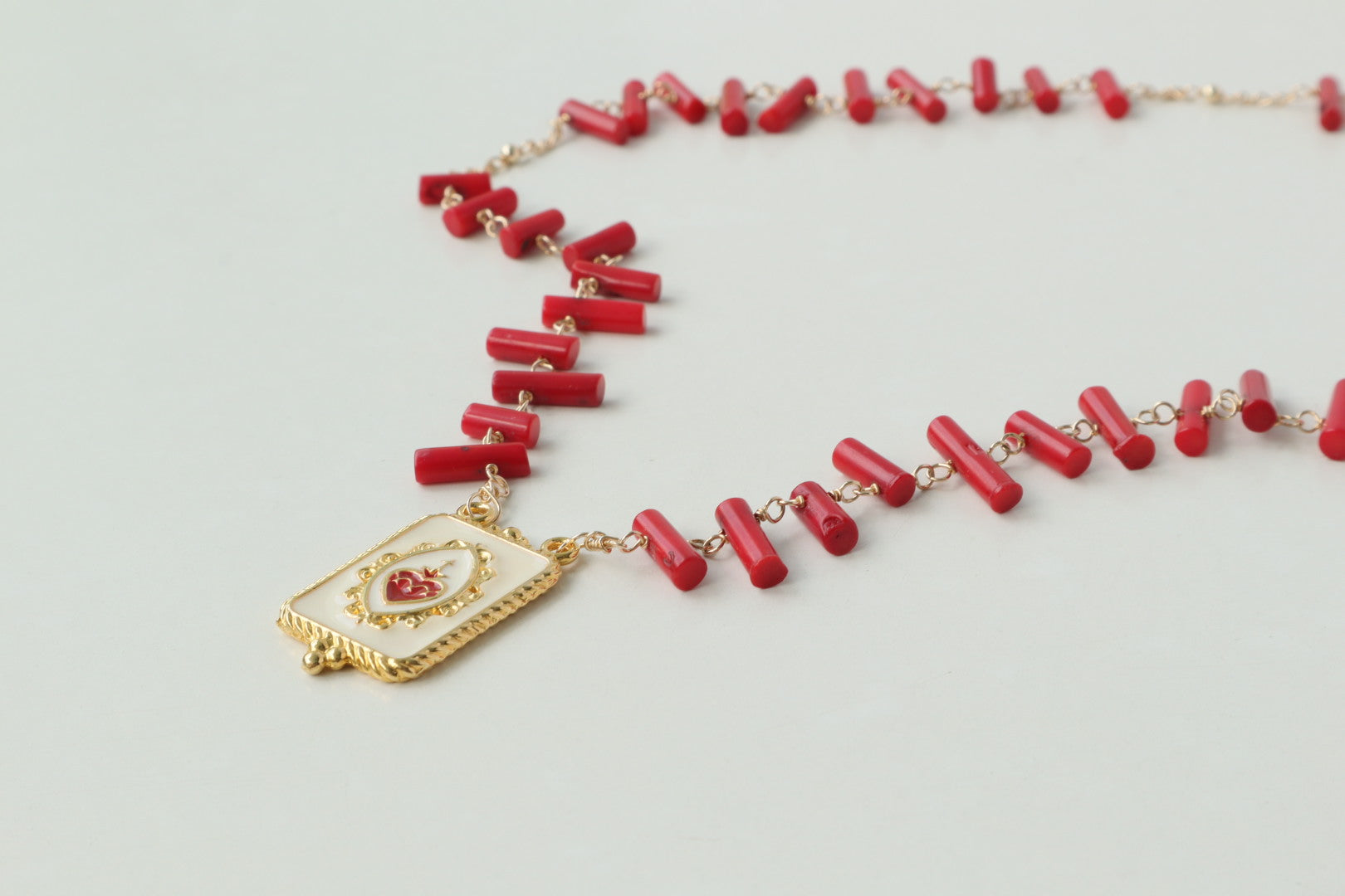 Vibrant coral beads, a touch of the sea, dance on a delicate gold-filled chain, accented by a captivating gold-filled enamel pendant.