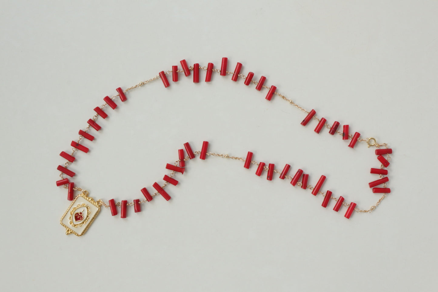 Vibrant coral beads, a touch of the sea, dance on a delicate gold-filled chain, accented by a captivating gold-filled enamel pendant.