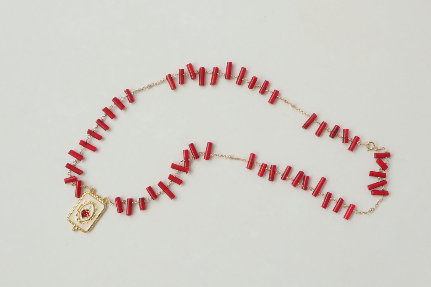 Vibrant coral beads, a touch of the sea, dance on a delicate gold-filled chain, accented by a captivating gold-filled enamel pendant.