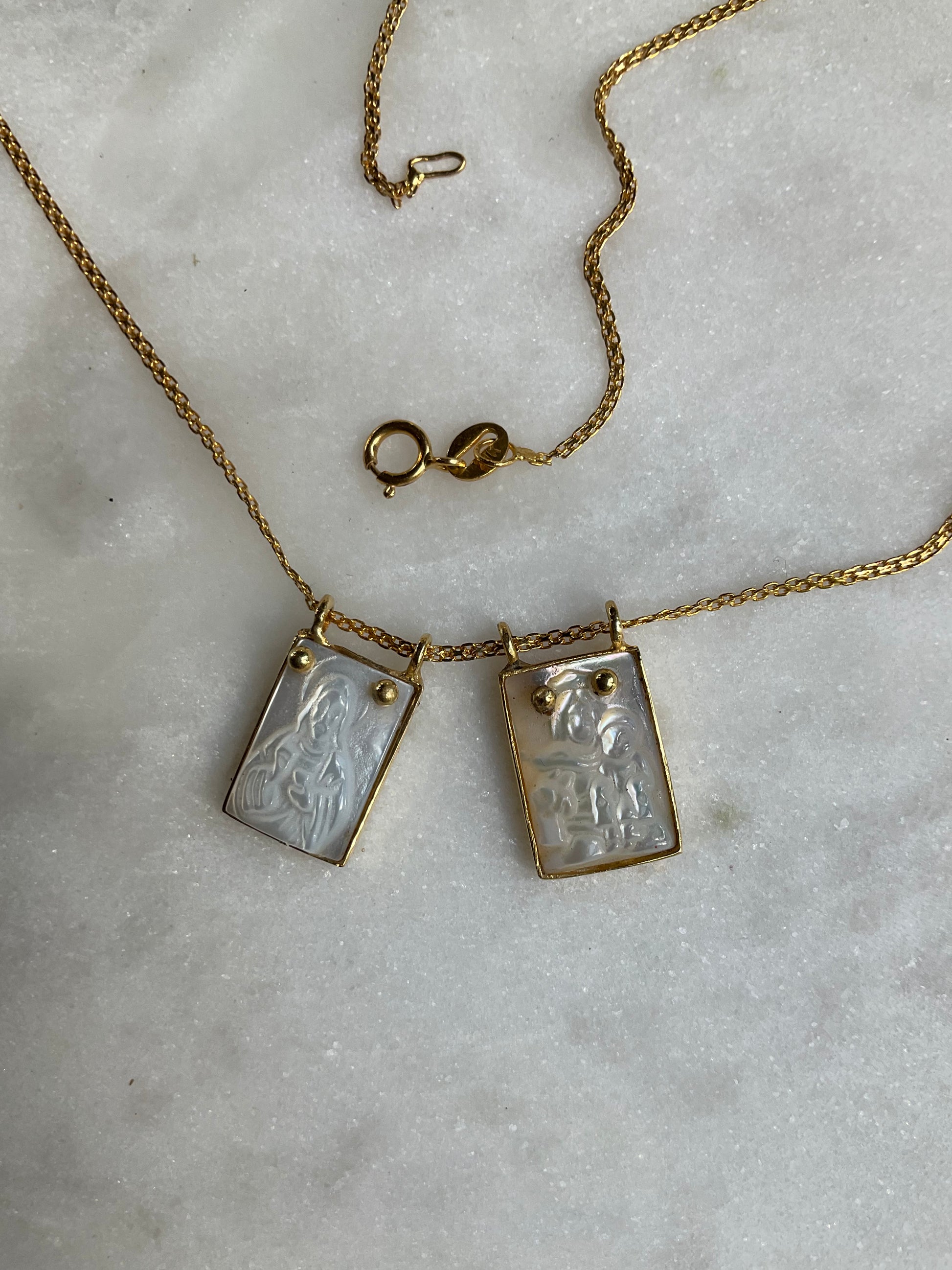 A timeless depiction of faith. Etched mother-of-pearl portrays Jesus and Mary, encased in gleaming 14k gold. A treasured pendant to be cherished for generations.