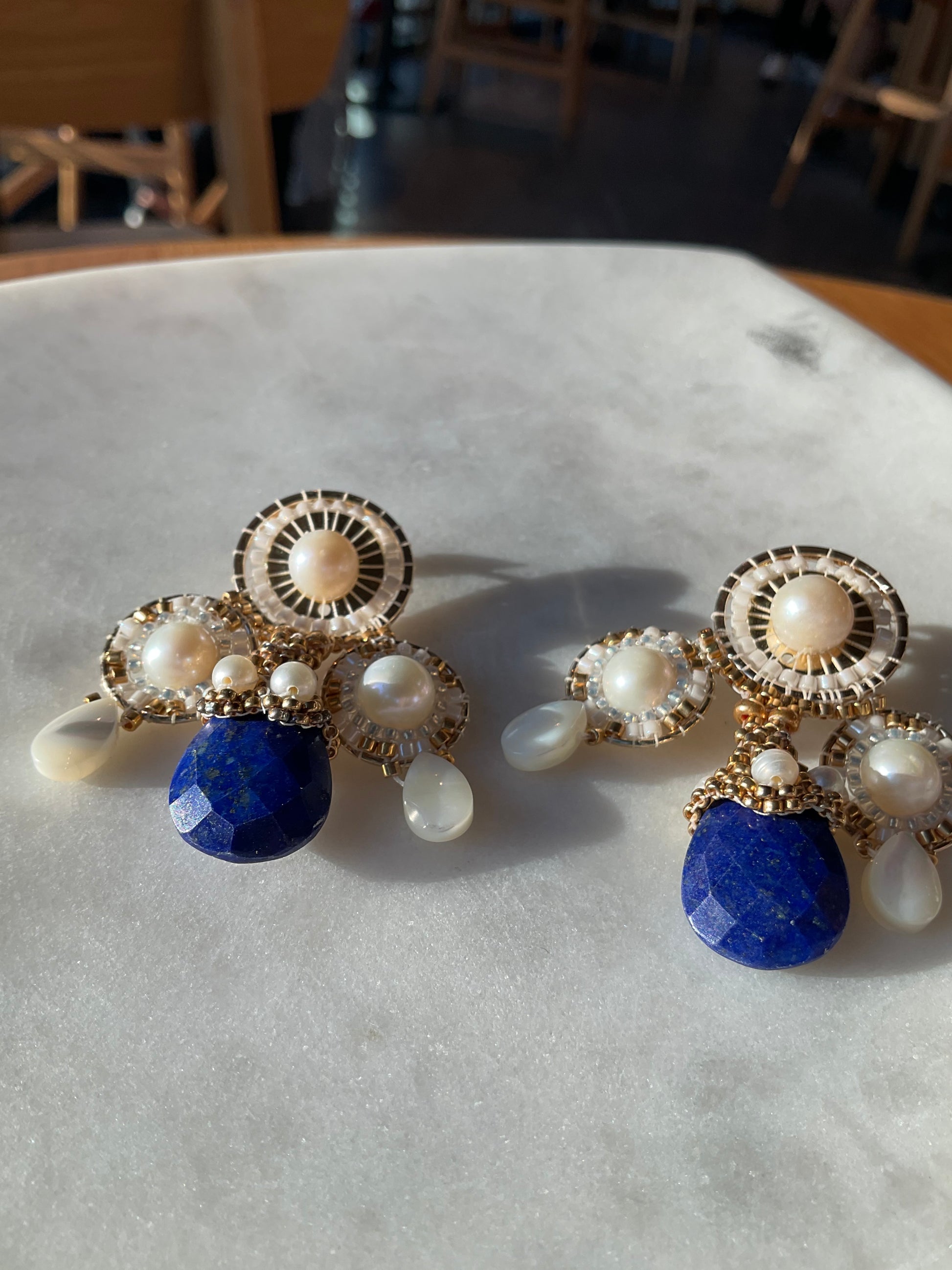 18k gold-filled posts showcase handwoven pearls, culminating in captivating lapis lazuli drops. Each stone is embraced by an intricate pearl and Miyuki bead cap, a testament to meticulous artistry.