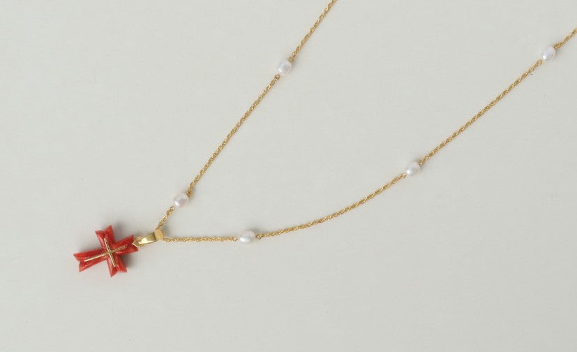 Luminous freshwater pearls add a touch of elegance, while the stunning Japanese coral cross pendant, in a fiery shade of red, takes center stage. The coral is intricately detailed with an inlaid 18K gold cross, a symbol of hope and devotion. All elements are strung on a delicate 18K gold chain.