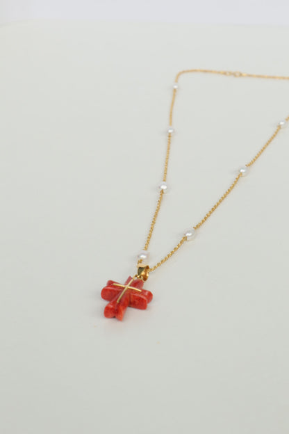 Luminous freshwater pearls add a touch of elegance, while the stunning Japanese coral cross pendant, in a fiery shade of red, takes center stage. The coral is intricately detailed with an inlaid 18K gold cross, a symbol of hope and devotion. All elements are strung on a delicate 18K gold chain.