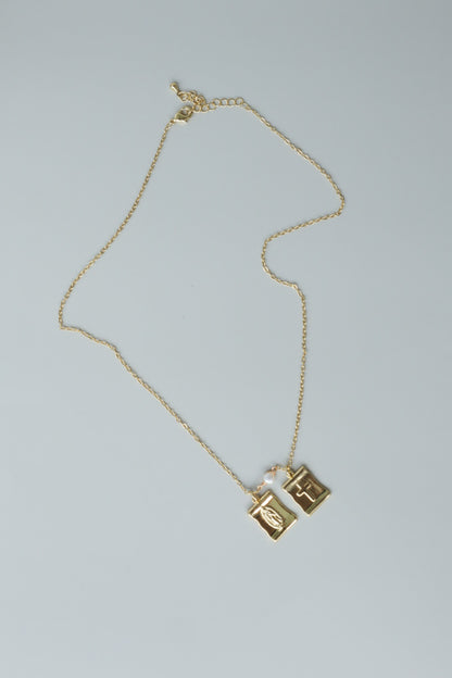 A gold-filled scapular pendant, a traditional symbol of faith, reimagined for modern wear.