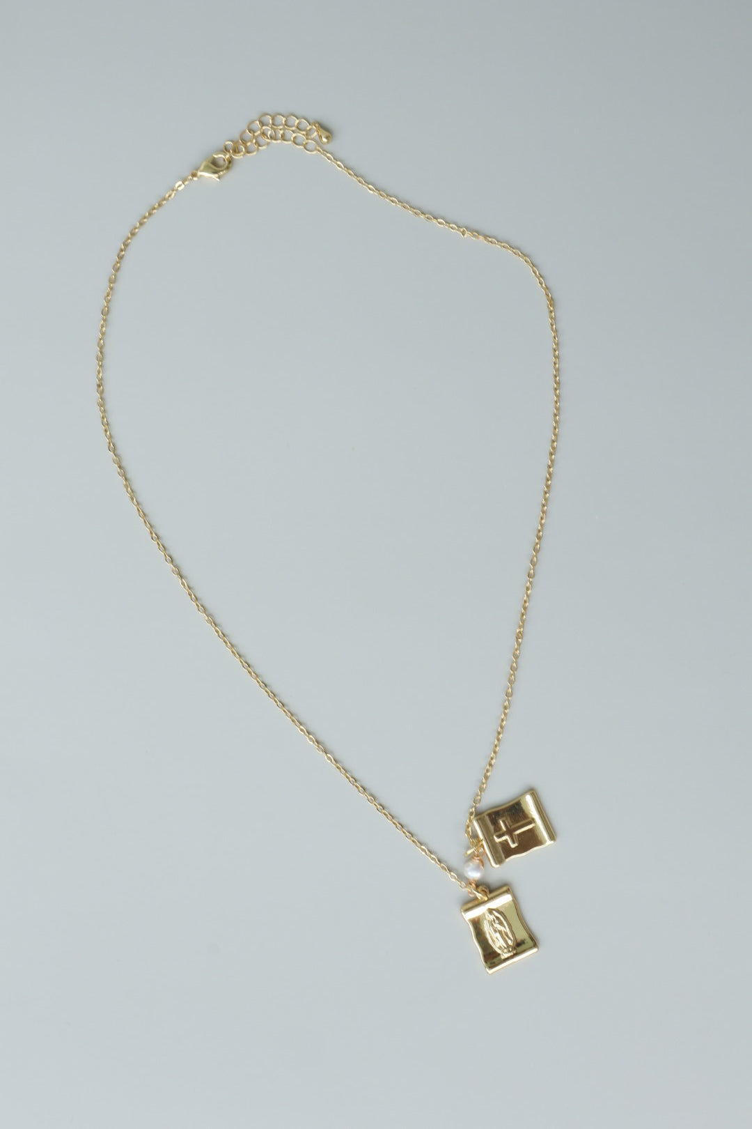 A gold-filled scapular pendant, a traditional symbol of faith, reimagined for modern wear.