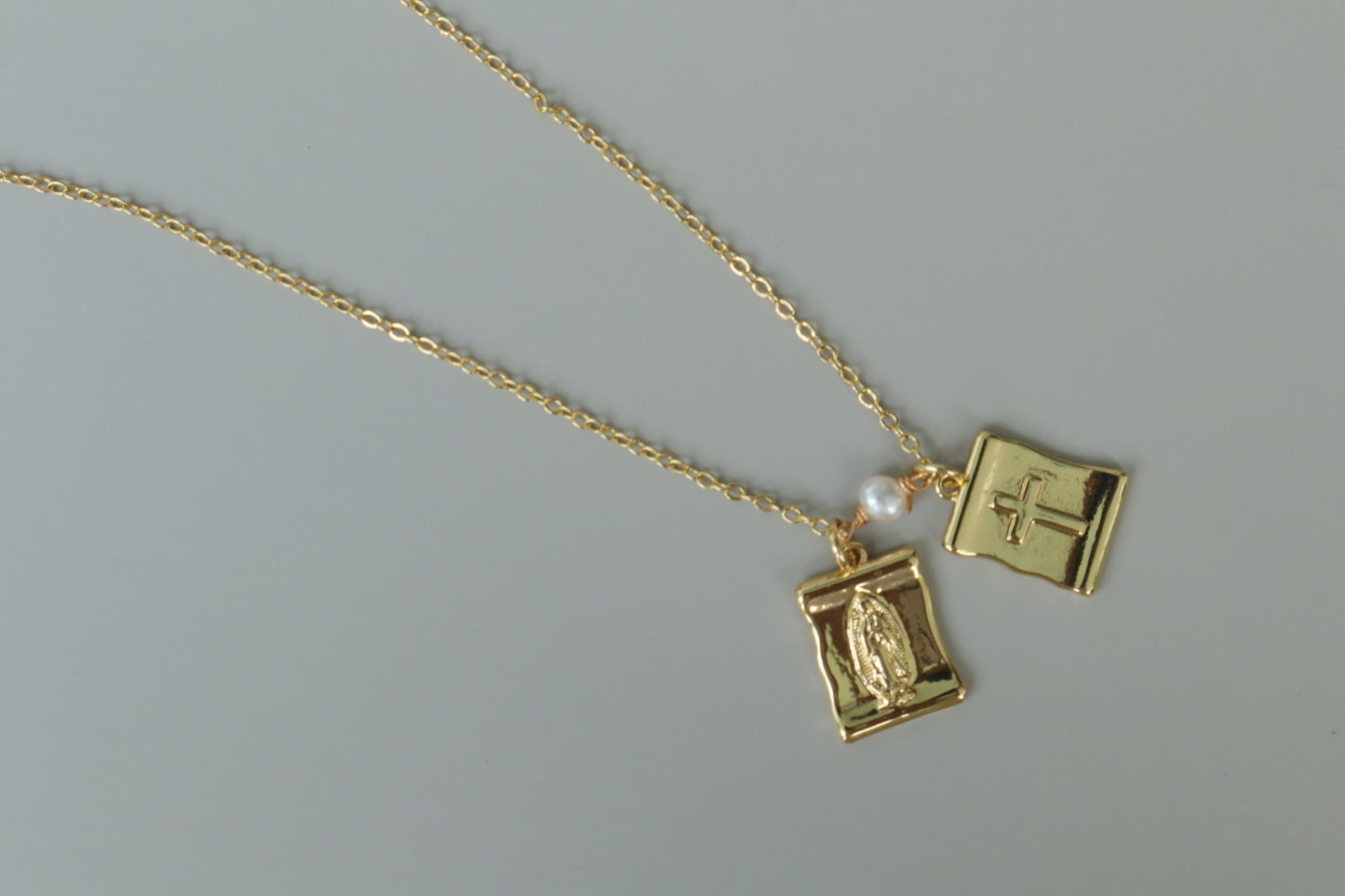 A gold-filled scapular pendant, a traditional symbol of faith, reimagined for modern wear.