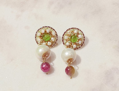 Celebrate a captivating interplay of gem and pearl with these 18k gold-filled earrings. Luminous peridot gemstones boast a refreshing lime green hue, symbolizing growth and prosperity. Tourmaline gemstones add a touch of vibrant color, mixing hues of deep pink to bright red. Organic baroque pearls whisper of elegance, while Keishi pearls add a touch of unique beauty. Secured on gleaming 18k gold-filled posts, these earrings are a captivating dance of texture, light, and symbolism.