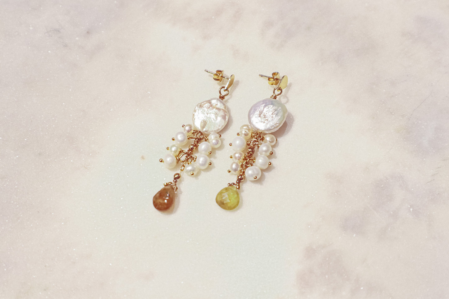 Embrace the organic elegance of these one-of-a-kind earrings. Baroque and freshwater pearls, boasting their unique shapes and textures, are meticulously woven together on sleek gold-filled findings. Shimmering Vessonite teardrops add a touch of vibrant green, creating a captivating contrast that reflects the beauty of nature's symphony.