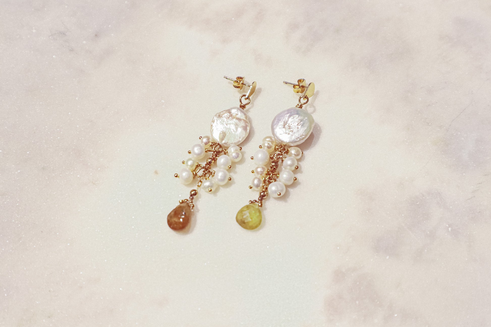 Embrace the organic elegance of these one-of-a-kind earrings. Baroque and freshwater pearls, boasting their unique shapes and textures, are meticulously woven together on sleek gold-filled findings. Shimmering Vessonite teardrops add a touch of vibrant green, creating a captivating contrast that reflects the beauty of nature's symphony.