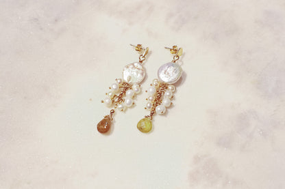 Embrace the organic elegance of these one-of-a-kind earrings. Baroque and freshwater pearls, boasting their unique shapes and textures, are meticulously woven together on sleek gold-filled findings. Shimmering Vessonite teardrops add a touch of vibrant green, creating a captivating contrast that reflects the beauty of nature's symphony.