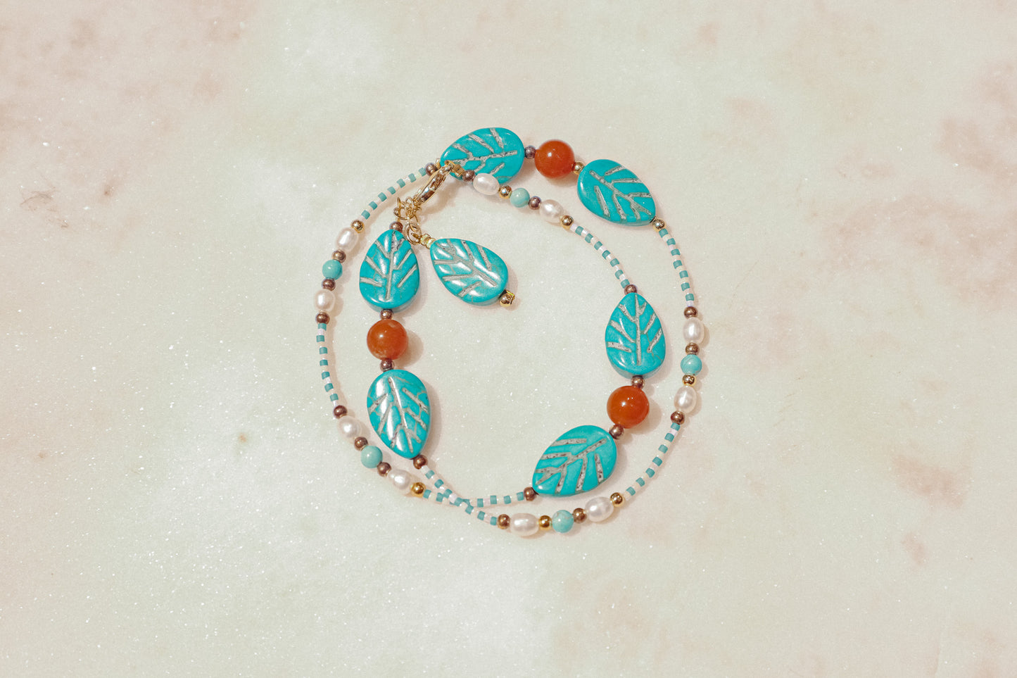 A symphony of the sea. Luminous pearls, shimmering mother-of-pearl, vibrant turquoise, and pops of coral dance on a gold-filled chain on this choker necklace.