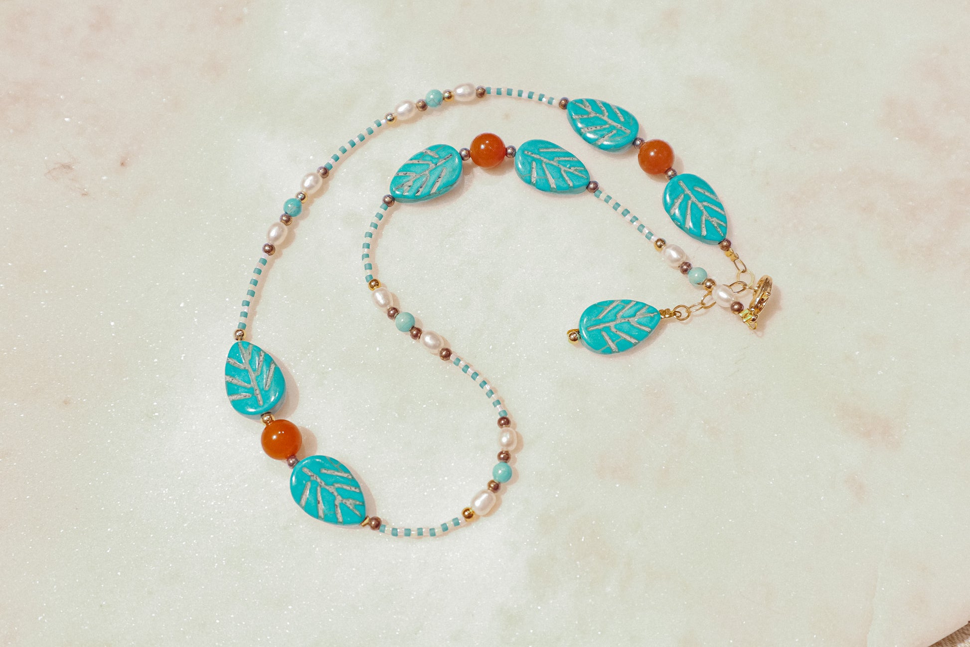 A symphony of the sea. Luminous pearls, shimmering mother-of-pearl, vibrant turquoise, and pops of coral dance on a gold-filled chain on this choker necklace.