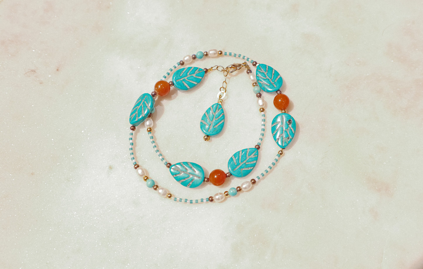 A symphony of the sea. Luminous pearls, shimmering mother-of-pearl, vibrant turquoise, and pops of coral dance on a gold-filled chain on this choker necklace.