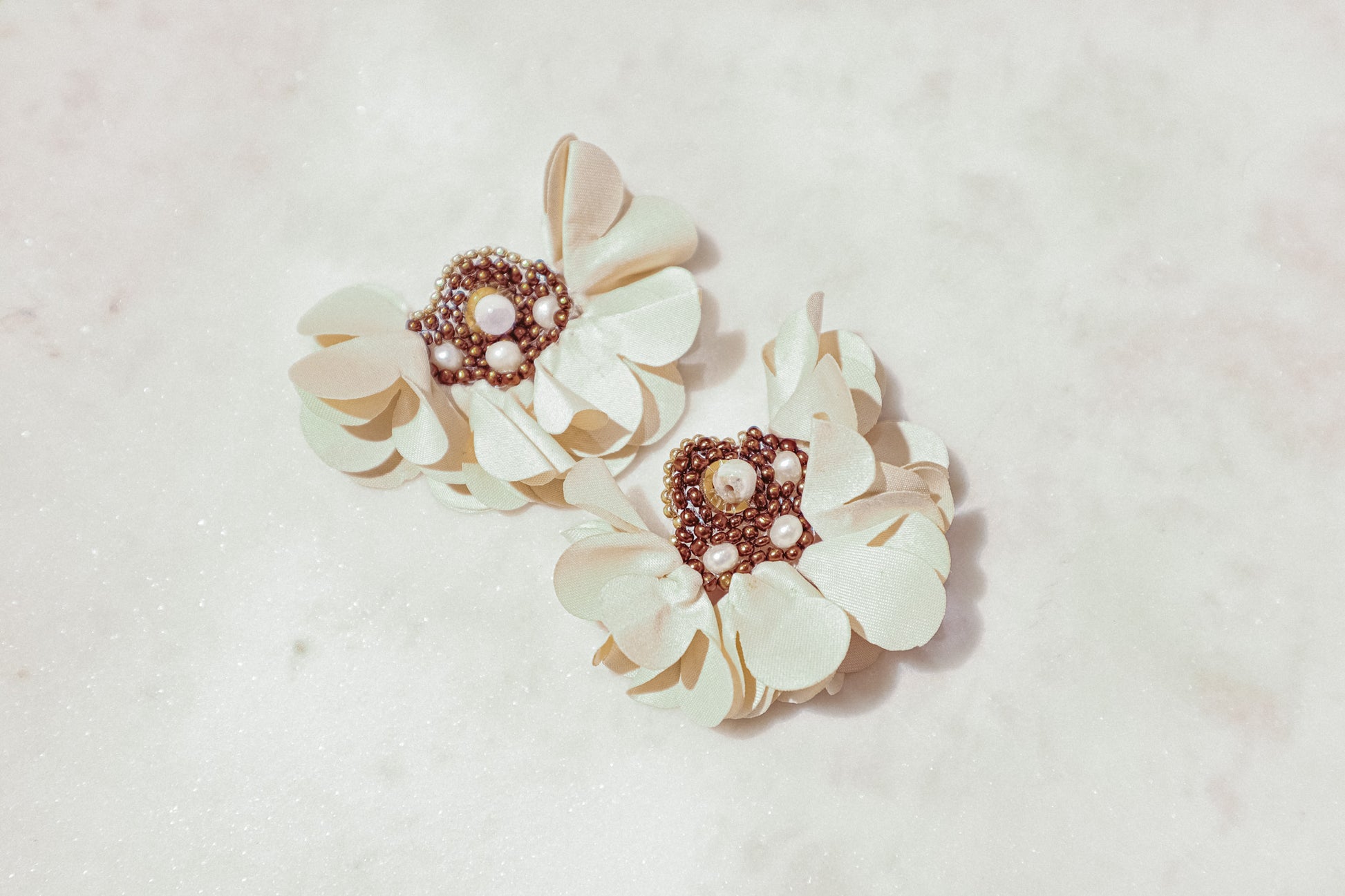 Introducing our exquisite floral earrings, crafted with meticulous attention to detail. Each pair features delicate fabric flowers adorned with lustrous freshwater pearls, complemented by a gold-plated stainless steel post. Elevate your elegance with this timeless accessory, perfect for any discerning jewelry connoisseur.