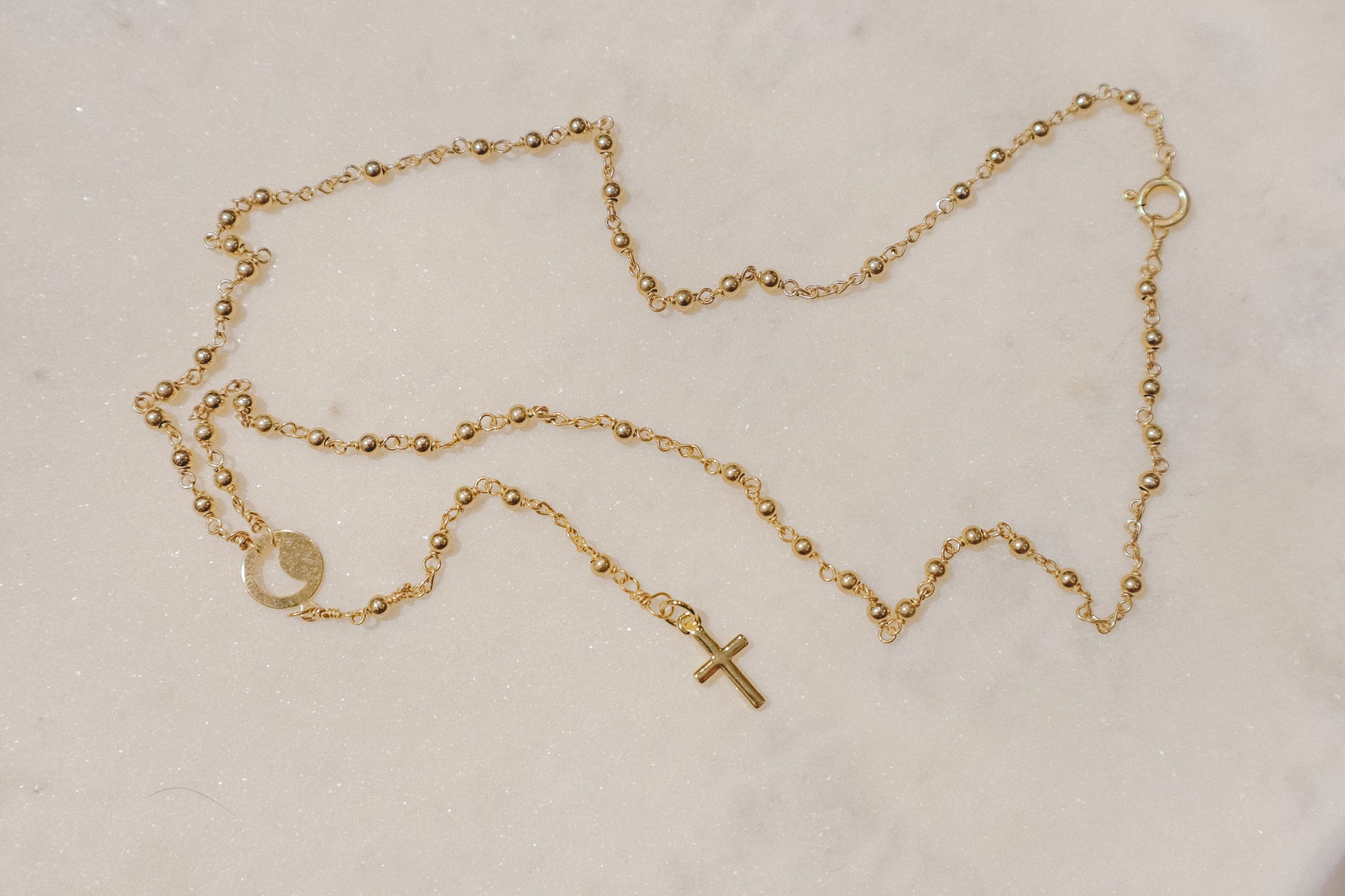 A gleaming gold-filled cross rests upon a captivating ball and wire chain, both crafted in polished gold-filled metal in this simple and elegant rosary.