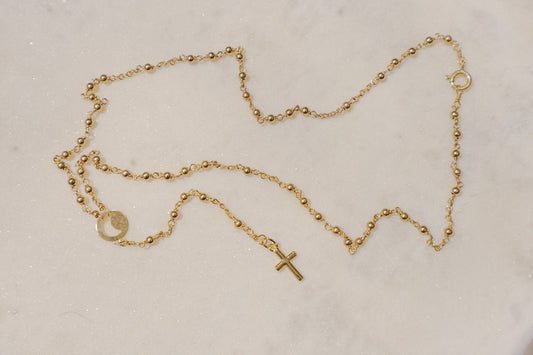 A gleaming gold-filled cross rests upon a captivating ball and wire chain, both crafted in polished gold-filled metal in this simple and elegant rosary.