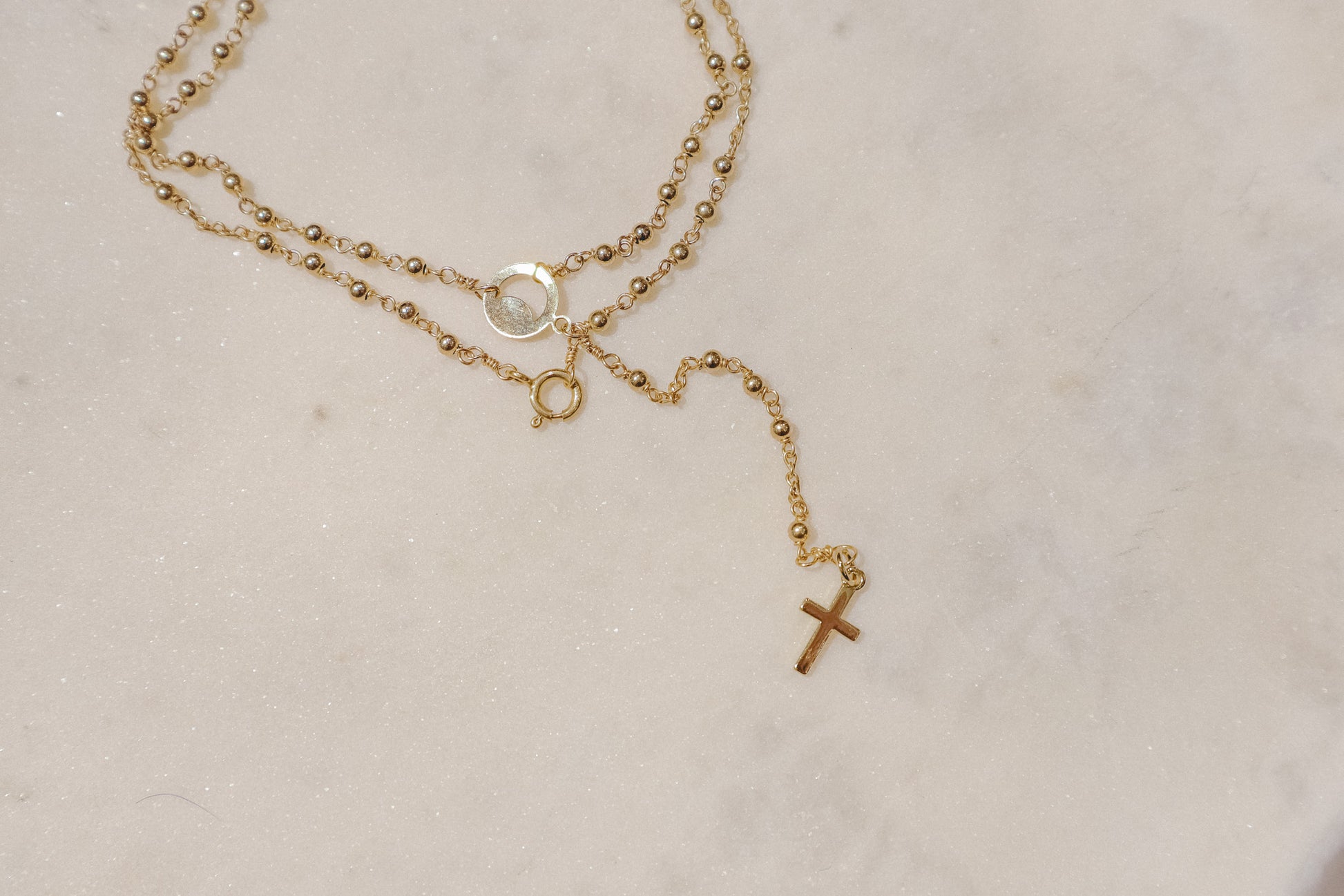 A gleaming gold-filled cross rests upon a captivating ball and wire chain, both crafted in polished gold-filled metal in this simple and elegant rosary.