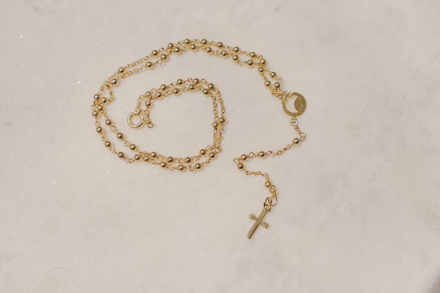 A gleaming gold-filled cross rests upon a captivating ball and wire chain, both crafted in polished gold-filled metal in this simple and elegant rosary.