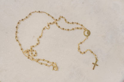 A gleaming gold-filled cross rests upon a captivating ball and wire chain, both crafted in polished gold-filled metal in this simple and elegant rosary.