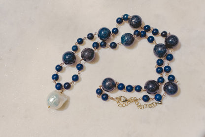 Rich lapis lazuli beads, a touch of the sea and sky, dance on a gleaming gold-filled wire chain. A luminous baroque pearl takes center stage, creating this statement piece necklace of simple beauty.