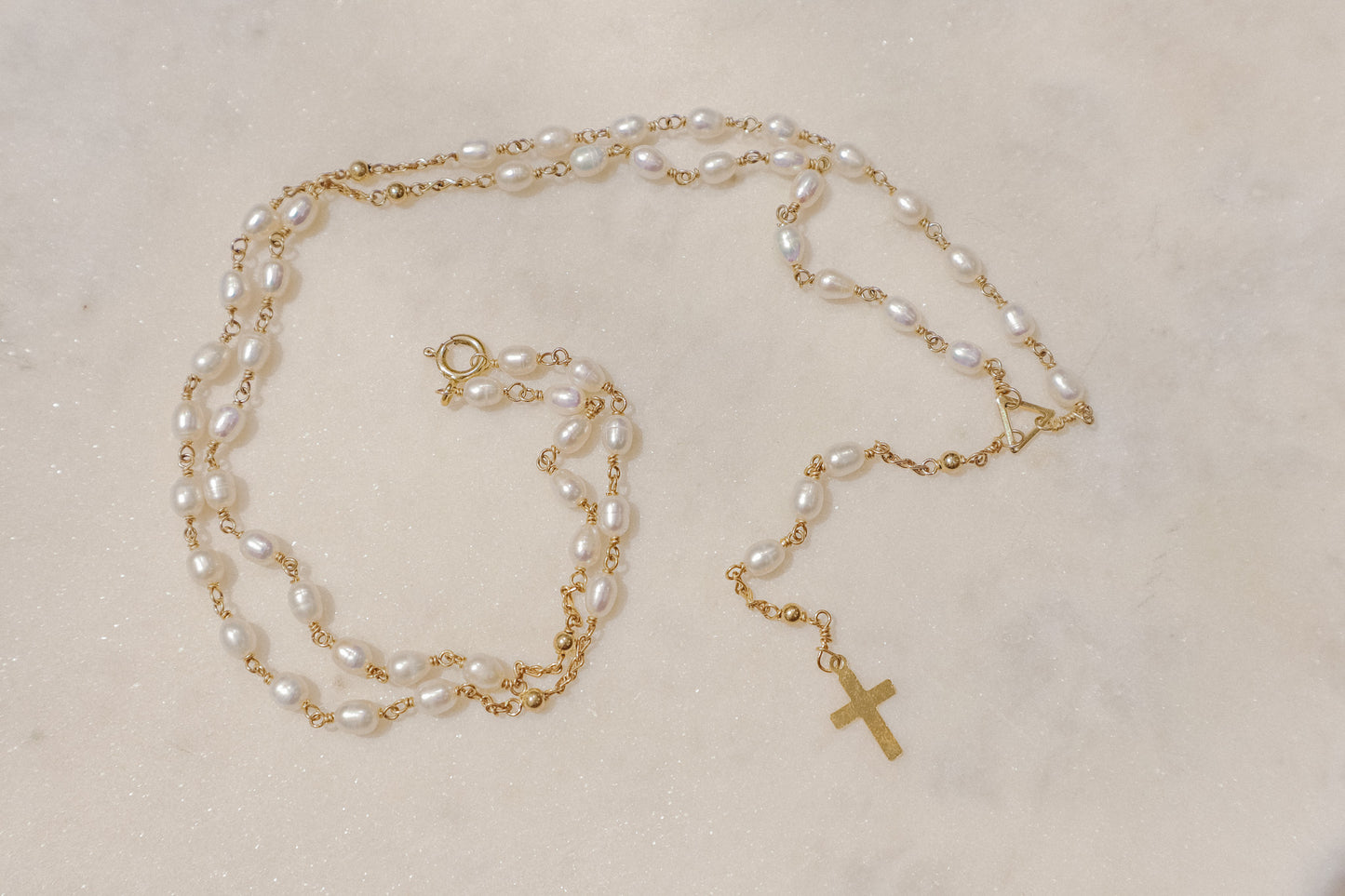 Luminous pearls, timeless symbols of purity and faith, adorn a delicate gold-filled wire chain.