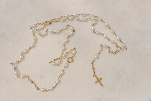 Luminous pearls, timeless symbols of purity and faith, adorn a delicate gold-filled wire chain.