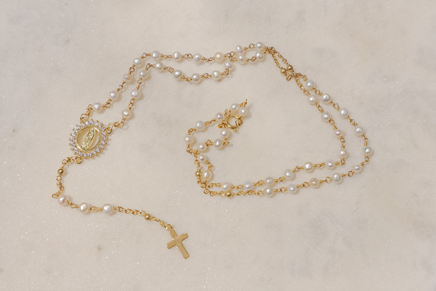 Luminous pearls, symbolic of purity and wisdom, adorn a delicate chain, culminating in a radiant CZ Mother Mary pendant. A beautiful companion for moments of reflection and connection with your inner light and divine guidance.