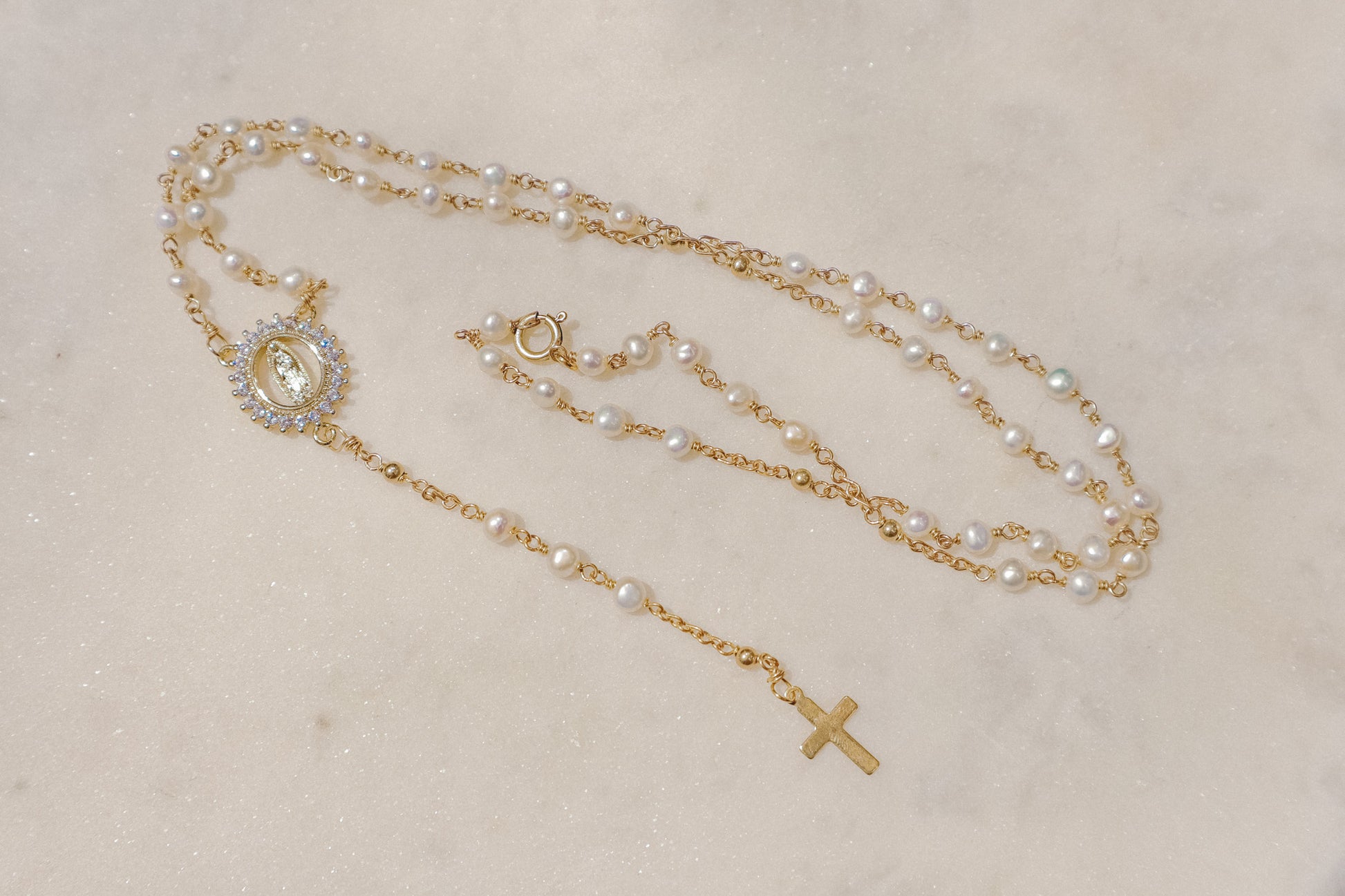 Luminous pearls, symbolic of purity and wisdom, adorn a delicate chain, culminating in a radiant CZ Mother Mary pendant. A beautiful companion for moments of reflection and connection with your inner light and divine guidance.