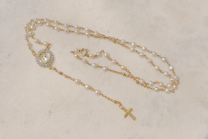 Luminous pearls, symbolic of purity and wisdom, adorn a delicate chain, culminating in a radiant CZ Mother Mary pendant. A beautiful companion for moments of reflection and connection with your inner light and divine guidance.