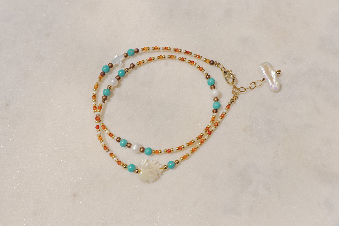 A symphony of the sea. Luminous pearls, shimmering mother-of-pearl, vibrant turquoise, and pops of coral dance on a gold-filled chain.