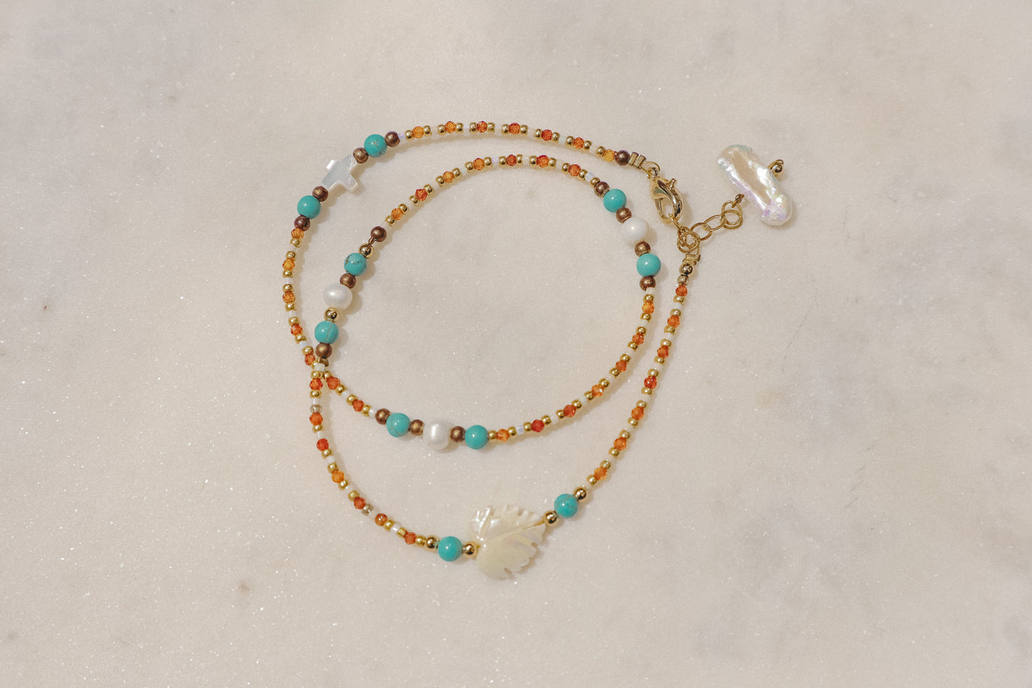 A symphony of the sea. Luminous pearls, shimmering mother-of-pearl, vibrant turquoise, and pops of coral dance on a gold-filled chain.