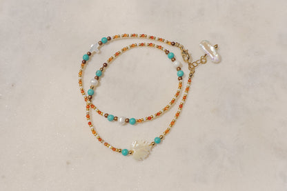 A symphony of the sea. Luminous pearls, shimmering mother-of-pearl, vibrant turquoise, and pops of coral dance on a gold-filled chain.