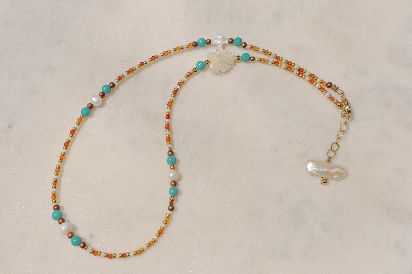 A symphony of the sea. Luminous pearls, shimmering mother-of-pearl, vibrant turquoise, and pops of coral dance on a gold-filled chain.