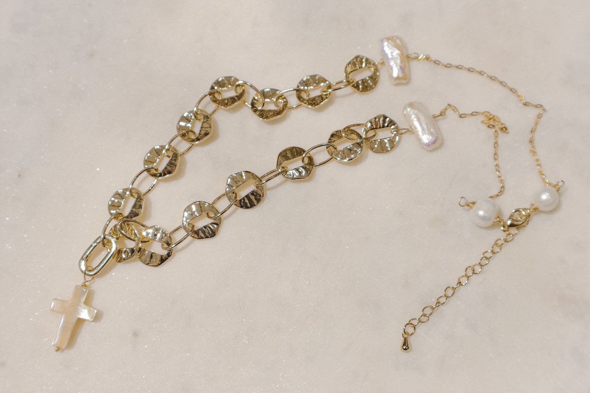 Freshwater pearls' timeless elegance rests on a shimmering gold-filled sand dollar chain, a symbol of protection. A delicate gold-filled enamel cross adds a touch of faith, creating a beautiful reminder of serenity and guidance.