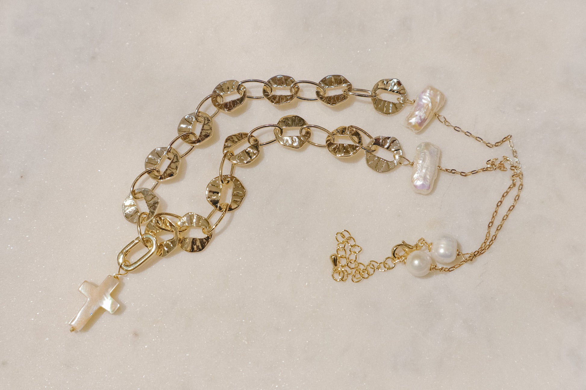 Freshwater pearls' timeless elegance rests on a shimmering gold-filled sand dollar chain, a symbol of protection. A delicate gold-filled enamel cross adds a touch of faith, creating a beautiful reminder of serenity and guidance.