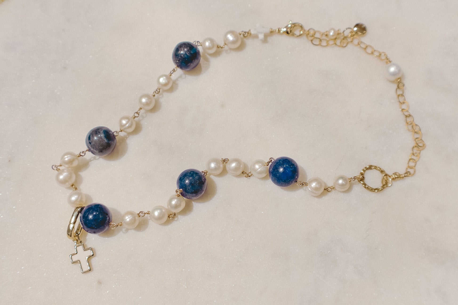 Embrace timeless elegance with a touch of bold beauty. This captivating gold-filled necklace features luminous pearls, a symbol of classic sophistication. The deep blue hues of the lapis lazuli gemstones add a touch of intrigue and depth, creating a perfect harmony. Secured on a delicate gold-filled chain, this necklace is a versatile piece that can elevate any outfit.