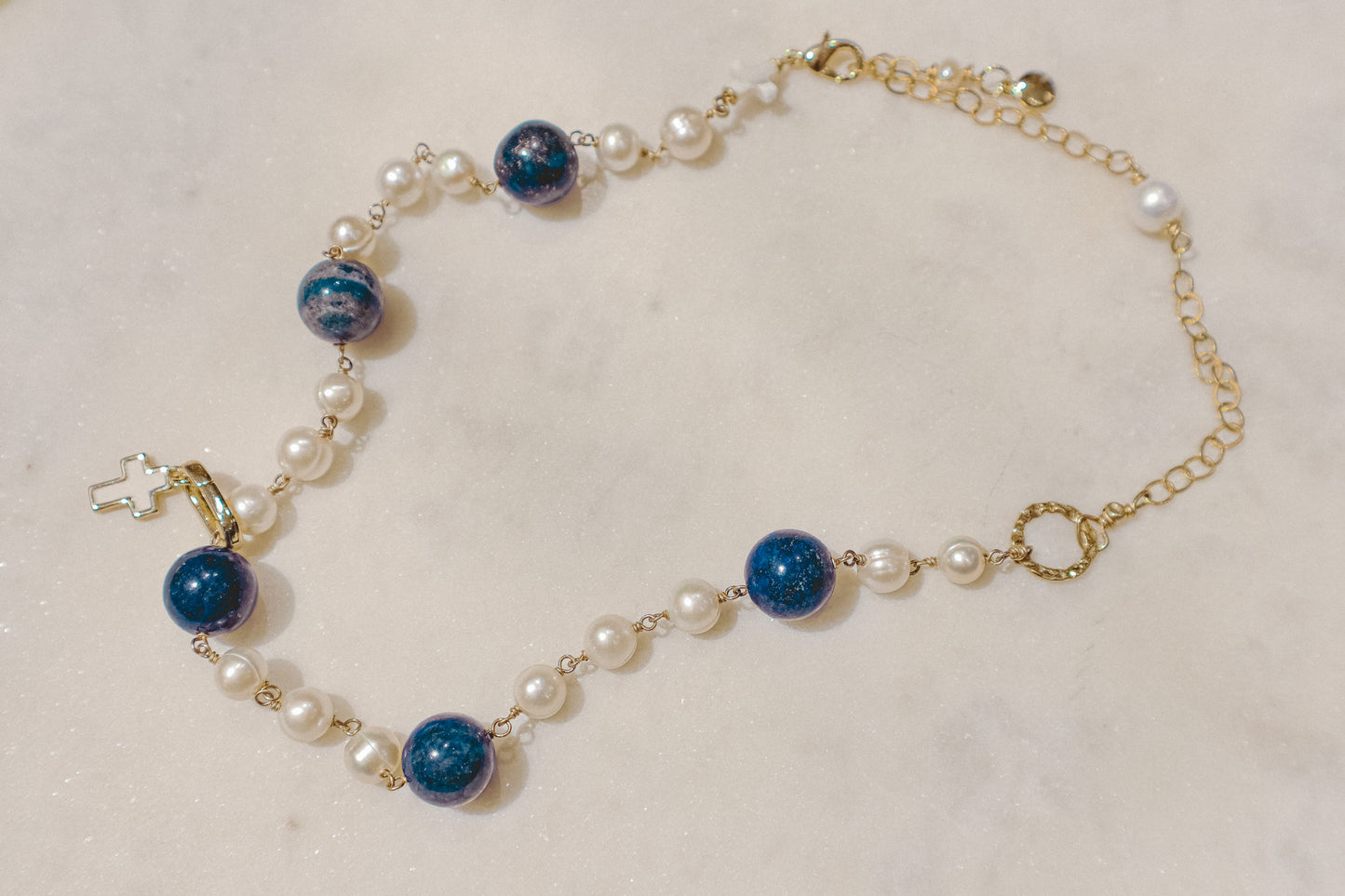 Embrace timeless elegance with a touch of bold beauty. This captivating gold-filled necklace features luminous pearls, a symbol of classic sophistication. The deep blue hues of the lapis lazuli gemstones add a touch of intrigue and depth, creating a perfect harmony. Secured on a delicate gold-filled chain, this necklace is a versatile piece that can elevate any outfit.