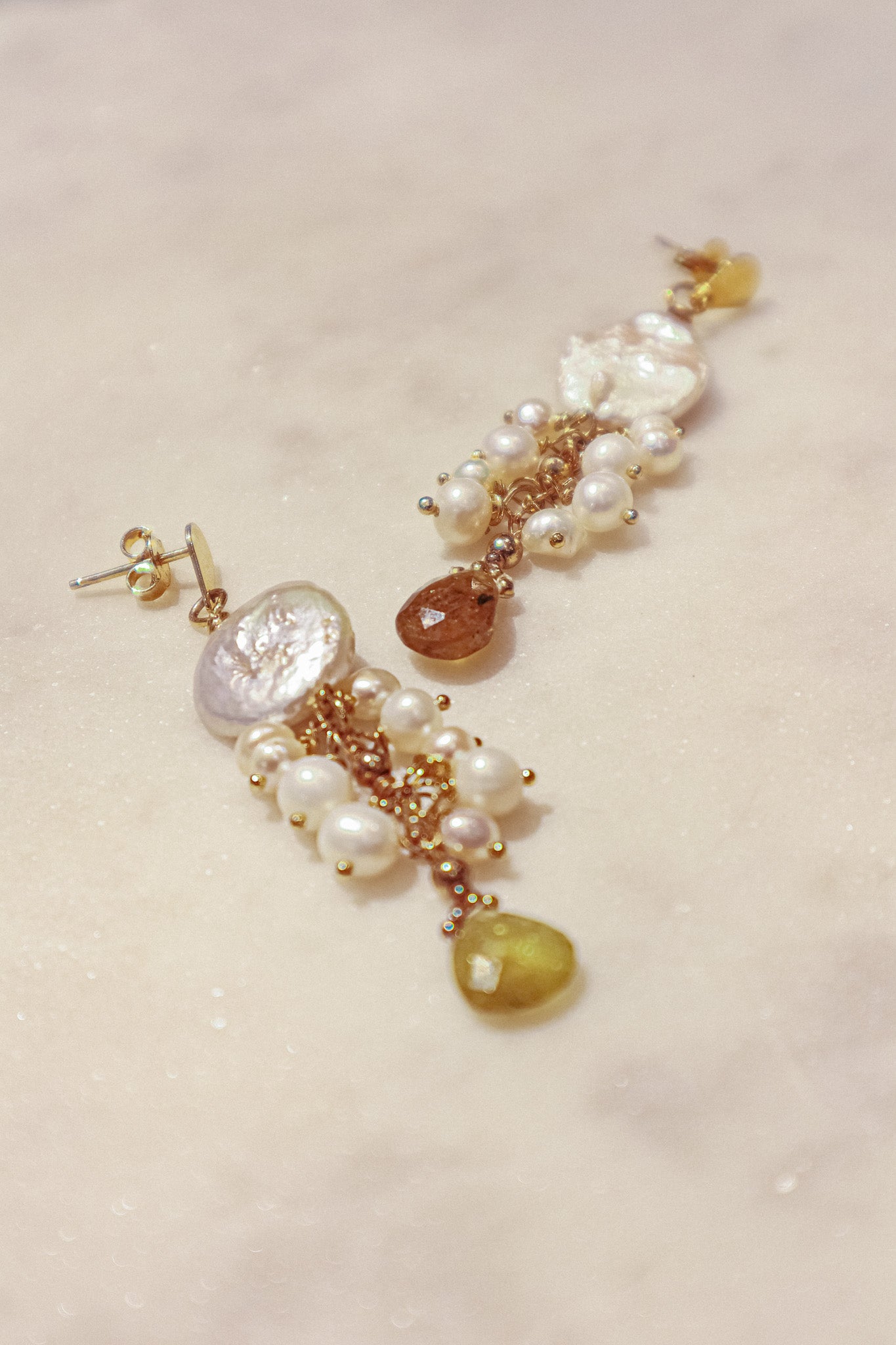 Embrace the organic elegance of these one-of-a-kind earrings. Baroque and freshwater pearls, boasting their unique shapes and textures, are meticulously woven together on sleek gold-filled findings. Shimmering Vessonite teardrops add a touch of vibrant green, creating a captivating contrast that reflects the beauty of nature's symphony.