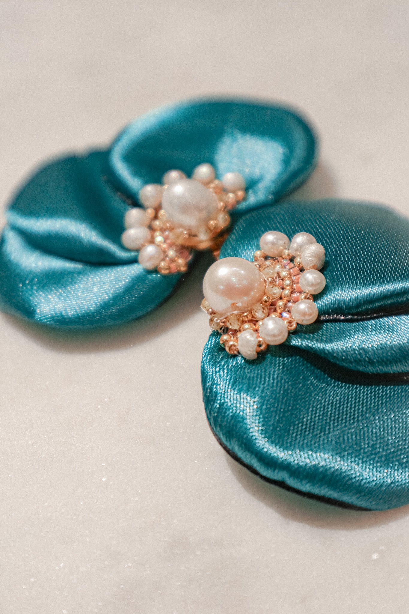 Celebrate the vibrant energy of summer with these captivating blue-green silk flower fan earrings. The meticulously embroidered design, featuring shimmering Miyuki beads, brings the flower to life. Delicate freshwater pearls and sparkling lemon sapphires add a touch of sophistication, making these earrings a perfect way to add a burst of color to any outfit.